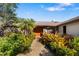 House entrance with a walkway, showcasing tropical landscaping and an orange double door at 917 S Doral Ln, Venice, FL 34293