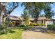 Single-story home with stone accents and a large driveway, surrounded by mature trees at 917 S Doral Ln, Venice, FL 34293