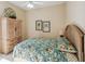 Bedroom with floral bedding, wooden dresser, and ceiling fan at 958 Chickadee Dr, Venice, FL 34285