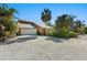 Home with a spacious gravel driveway, lush landscaping, and a convenient garage, providing ample parking at 140 N Casey Key Rd, Osprey, FL 34229