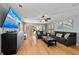 Bright living room features a large TV, ceiling fan, and access to the outdoors at 140 N Casey Key Rd, Osprey, FL 34229