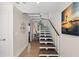 Bright foyer with hardwood floors and a modern white and wood staircase with a coastal theme at 140 N Casey Key Rd, Osprey, FL 34229