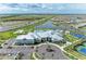 Aerial view of a modern clubhouse with a pool, sports courts, and ample parking in a lakeside community at 15917 Clear Skies Pl, Lakewood Ranch, FL 34211