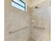 Modern bathroom shower with tile surround, window and grab bars at 15917 Clear Skies Pl, Lakewood Ranch, FL 34211