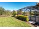 Landscaped backyard with grassy area and screened pool enclosure at 17459 Hickok Belt Loop, Bradenton, FL 34211