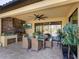 Covered outdoor kitchen with built-in grill, seating area, and ceiling fan at 17459 Hickok Belt Loop, Bradenton, FL 34211
