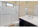 Bathroom with a walk-in shower, white tile, and dark vanity at 26720 Weiskopf Dr, Englewood, FL 34223