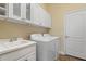 Laundry room with white cabinets, washer, dryer and sink at 26720 Weiskopf Dr, Englewood, FL 34223