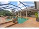 A screened in backyard pool is surrounded by brick, plants and a seating area at 505 Sand Crane Ct, Bradenton, FL 34212