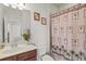Well-lit bathroom featuring a single vanity, toilet, and shower/tub combination with tropical-themed curtain at 7911 Moonstone Dr # 26-203, Sarasota, FL 34233