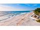 Scenic view of a sandy beach with calm ocean waves, palm trees, and lounge chairs under a clear sky at 7911 Moonstone Dr # 26-203, Sarasota, FL 34233