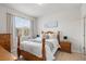 Bright bedroom with a wooden bed frame, side tables, and light-filled window view at 7911 Moonstone Dr # 26-203, Sarasota, FL 34233