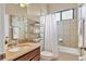 Well-lit bathroom featuring granite counters, single sink vanity, tub, and shower combo at 9214 Raes Creek Pl, Palmetto, FL 34221