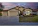 Charming single-story home with a three-car garage, manicured landscaping, and inviting curb appeal at sunset at 9214 Raes Creek Pl, Palmetto, FL 34221