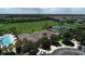 Aerial view featuring a community clubhouse, tennis court, pool, and surrounding lush green spaces at 10817 56Th St E, Parrish, FL 34219