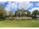 Welcoming community entrance with lush landscaping, mature palm trees, and attractive stone signage at 10817 56Th St E, Parrish, FL 34219