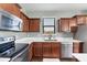 Kitchen featuring stainless steel microwave and oven, sink with window, quartz counters, and cherry wood cabinets at 10817 56Th St E, Parrish, FL 34219