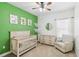 Adorable Bedroom featuring a crib, armchair, and green accent wall at 10931 Blue Magnolia Ln, Parrish, FL 34219