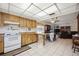 Open kitchen with white tile floors, wood cabinets, and an eat-in peninsula looks into the living area at 1119 76Th Nw St, Bradenton, FL 34209