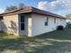 Neutral-toned home exterior shows corner, windows, and AC unit with an attached back door and partial view of a neighboring house at 22389 Elmira Blvd, Port Charlotte, FL 33952