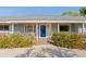 Inviting light blue home with a blue front door, rocking chairs, and well-manicured landscaping at 2329 Outer Dr, Sarasota, FL 34231