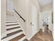 Stylish staircase featuring hardwood treads, white risers, a black handrail, and stone tile landing at 3360 Founders Club Dr, Sarasota, FL 34240