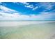 Wide sandy beach with clear, shallow water and a blue sky with scattered clouds at 380 Gulf Of Mexico Dr # 536, Longboat Key, FL 34228