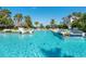 Spacious pool area with clear turquoise water, palm trees, and lounge chairs under a sunny sky at 380 Gulf Of Mexico Dr # 536, Longboat Key, FL 34228