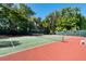 Well-maintained tennis court with green and red surface, surrounded by lush green trees at 380 Gulf Of Mexico Dr # 536, Longboat Key, FL 34228