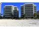 Two beachfront buildings with white sand and beach chairs at 6312 Midnight Pass Rd # 301S, Sarasota, FL 34242