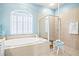 Bright bathroom featuring a soaking tub, tiled shower, and shuttered window at 7453 Featherstone Blvd, Sarasota, FL 34238