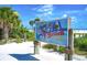 Sign proclaiming 'Siesta Beach, #1 Beach in the USA', framed by tropical foliage and pristine white sand at 7453 Featherstone Blvd, Sarasota, FL 34238