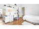 Well-lit bedroom with a large white desk, floating shelves, and wood-look floors at 7453 Featherstone Blvd, Sarasota, FL 34238