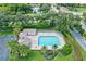 Aerial shot of a community pool featuring a bathhouse, lounge area, ample parking, and beautiful green landscaping at 7453 Featherstone Blvd, Sarasota, FL 34238