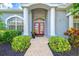 Inviting front entrance with red double doors, columns, and manicured greenery at 7453 Featherstone Blvd, Sarasota, FL 34238