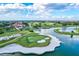 Aerial view of golf course showcasing lush green fairways, a lake, and a clubhouse under a sunny, partly cloudy sky at 7453 Featherstone Blvd, Sarasota, FL 34238