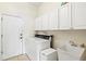 Well-lit laundry room featuring white cabinetry, a utility sink, and a modern washer/dryer at 7453 Featherstone Blvd, Sarasota, FL 34238