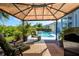 Relaxing outdoor patio with gazebo, rug, chairs and pool view offers outdoor living at its finest at 7453 Featherstone Blvd, Sarasota, FL 34238