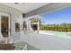 A partially covered patio with white furniture overlooking a bright blue pool and lush landscaping at 7453 Featherstone Blvd, Sarasota, FL 34238