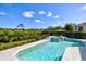 A sparkling pool and hot tub combo with lush landscaping and partial view of the home's exterior at 7453 Featherstone Blvd, Sarasota, FL 34238