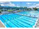 Outdoor swimming pool area featuring multiple lanes, bleacher seating, and a partially covered deck, perfect for competitive swimming at 7453 Featherstone Blvd, Sarasota, FL 34238