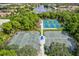 Aerial view of community tennis courts surrounded by green trees and a tranquil lake at 7453 Featherstone Blvd, Sarasota, FL 34238