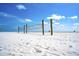 Volleyball net on a wide stretch of white sand under a clear blue sky, inviting beachgoers for fun games at 7453 Featherstone Blvd, Sarasota, FL 34238