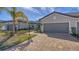 Exterior view of a house with a two-car garage, walkway, and palm trees in the front at 7590 Summerland Cv, Bradenton, FL 34202