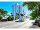 Exterior building view of a towering condo building with tropical trees, landscaping, and gated access at 9397 Midnight Pass Rd # 603, Sarasota, FL 34242