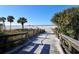 A sandy path leads to a serene beach lined with lush palm trees at 126/128 Avenida Veneccia, Sarasota, FL 34242