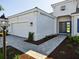 An exterior view of a grey one-story house with a two-car garage, blue door, and brick-paved walkway at 15610 San Lazzaro Ave, Bradenton, FL 34211