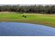 Scenic golf course view with pond, lush greenery, and golf carts under a sunny sky at 15610 San Lazzaro Ave, Bradenton, FL 34211