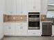 Bright kitchen features white cabinets, stainless steel appliances, and a stylish tiled backsplash at 15610 San Lazzaro Ave, Bradenton, FL 34211