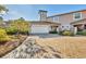 Tan two-story townhome with white garage door, brick driveway, and lush landscaping at 1719 Starling Dr # 1719, Sarasota, FL 34231